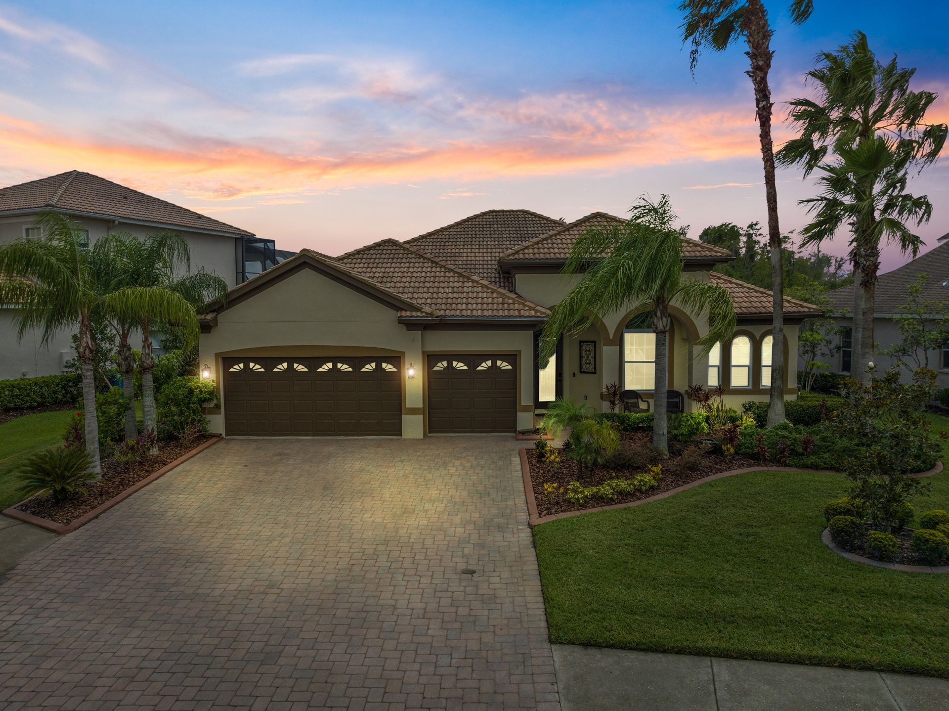 Beautiful suburban home with a tile roof and palm trees at sunset.